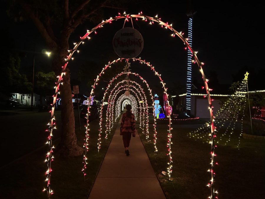 A young girl walking through a tunnel of arches decorated with mistletoe and Merry Christmas signs.