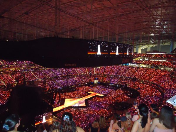 Red and purple lights show the large amount of people who attend a concert at the SoFi stadium.