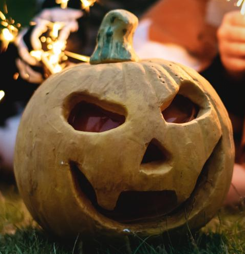 Halloween jack-o-lantern with a carved smile with festive sparklers in the background