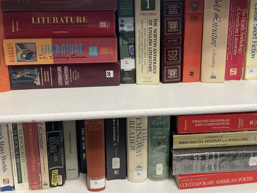 Large books on a wooden bookshelf inside of an English classroom.