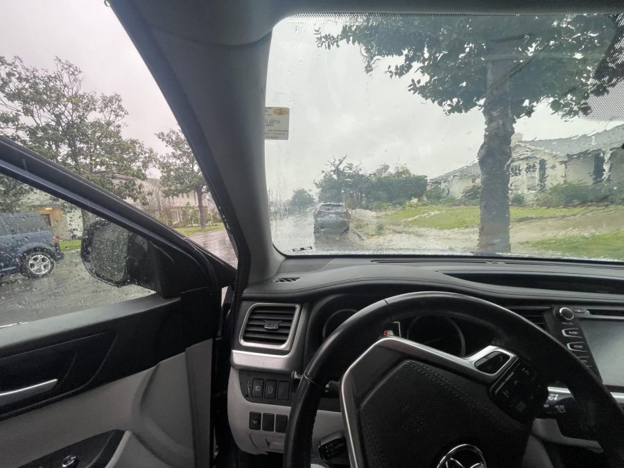 The view out of the front view window of a car on a  rainy day.