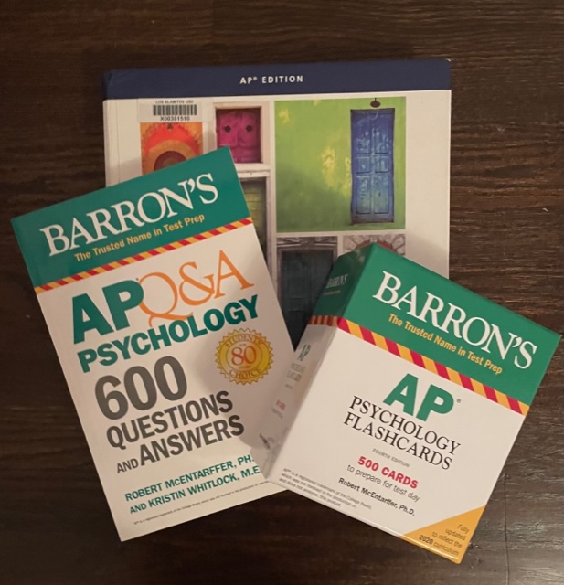 AP Psychology textbook provided by the school underneath the flashcards and practice questions created by the company Barrons test prep company.