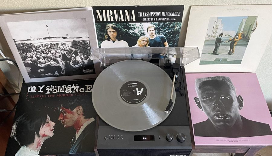 A turntable playing a silver record surrounded by other records