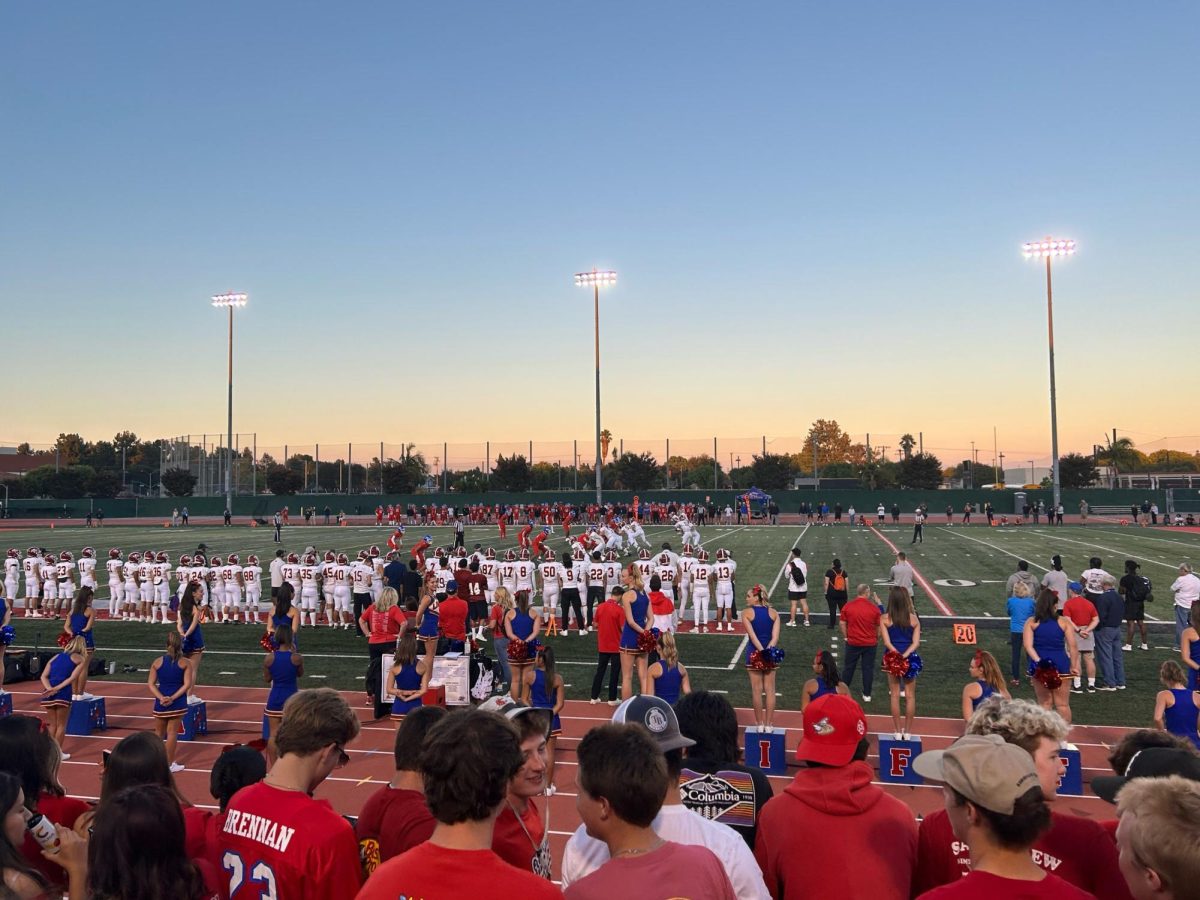 Los Al Locos eagerly watch the action on the football field while the Varsity cheer team hypes the crowd.