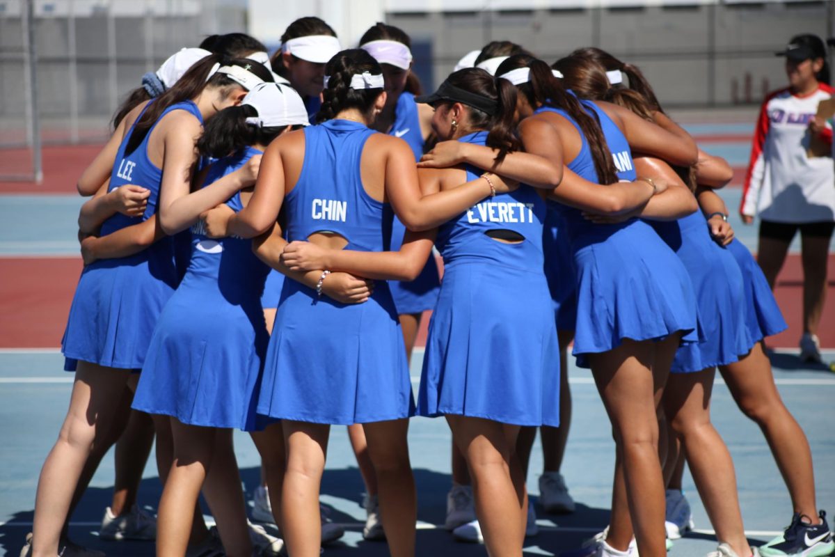 The girls varsity tennis team huddles together in preparation for their match on Sept. 7.
