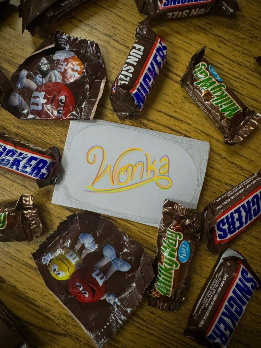 Chocolate bar from the Wonka movie surrounded by other name brand chocolates.