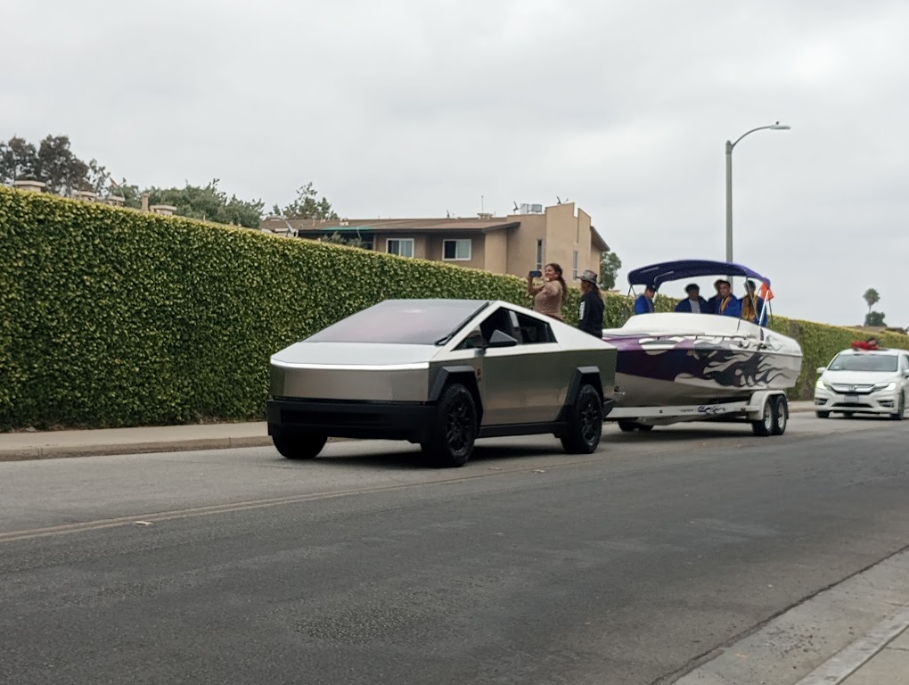 Los Al seniors ride in a boat, which is towed by a Tesla Cybertruck, during the parade.