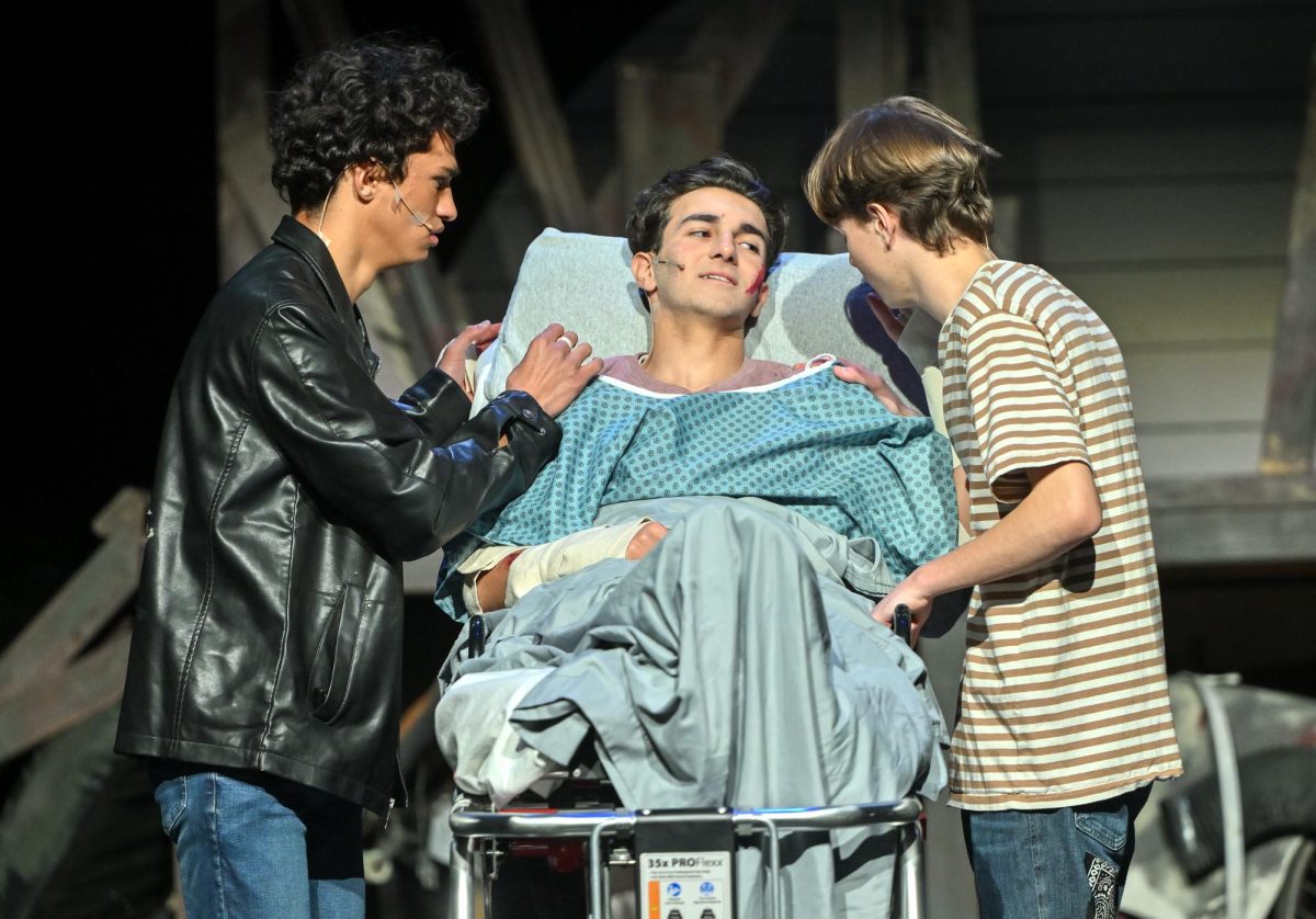 Dallas (left) and Ponyboy (right) comfort Johnny (center) in the hospital. (Photo courtesy of LAHS drama)