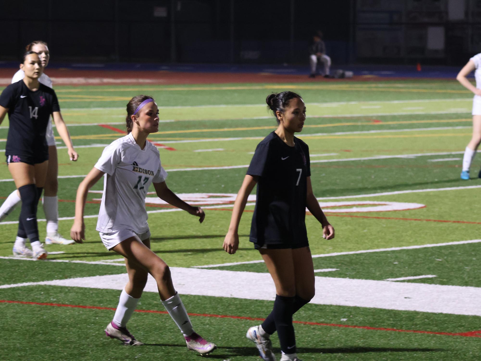 Vivi Zacharias walks across the field, tailed closely by the opposing team.