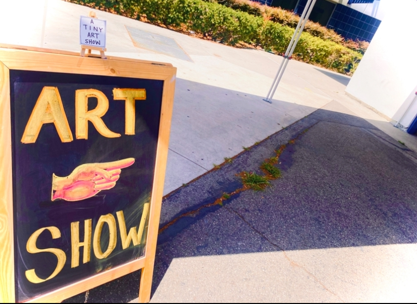 Sign advertising the art show along with another comically tiny sign