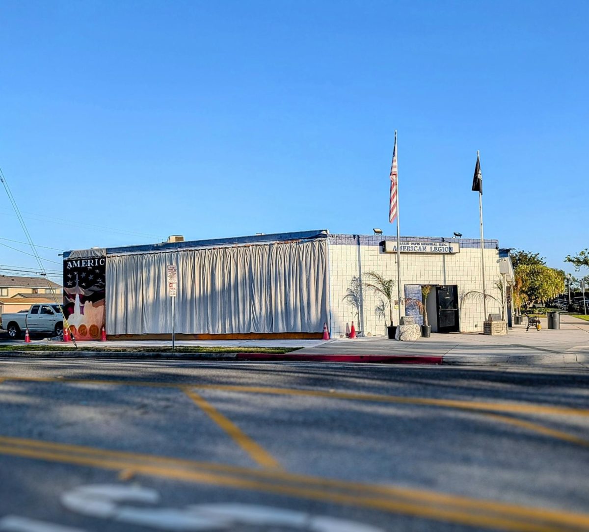 The American Legion Marin-Davis Post 716 building currently features a white curtain covering the in-progress mural, showing only a small portion of the grand art piece.
