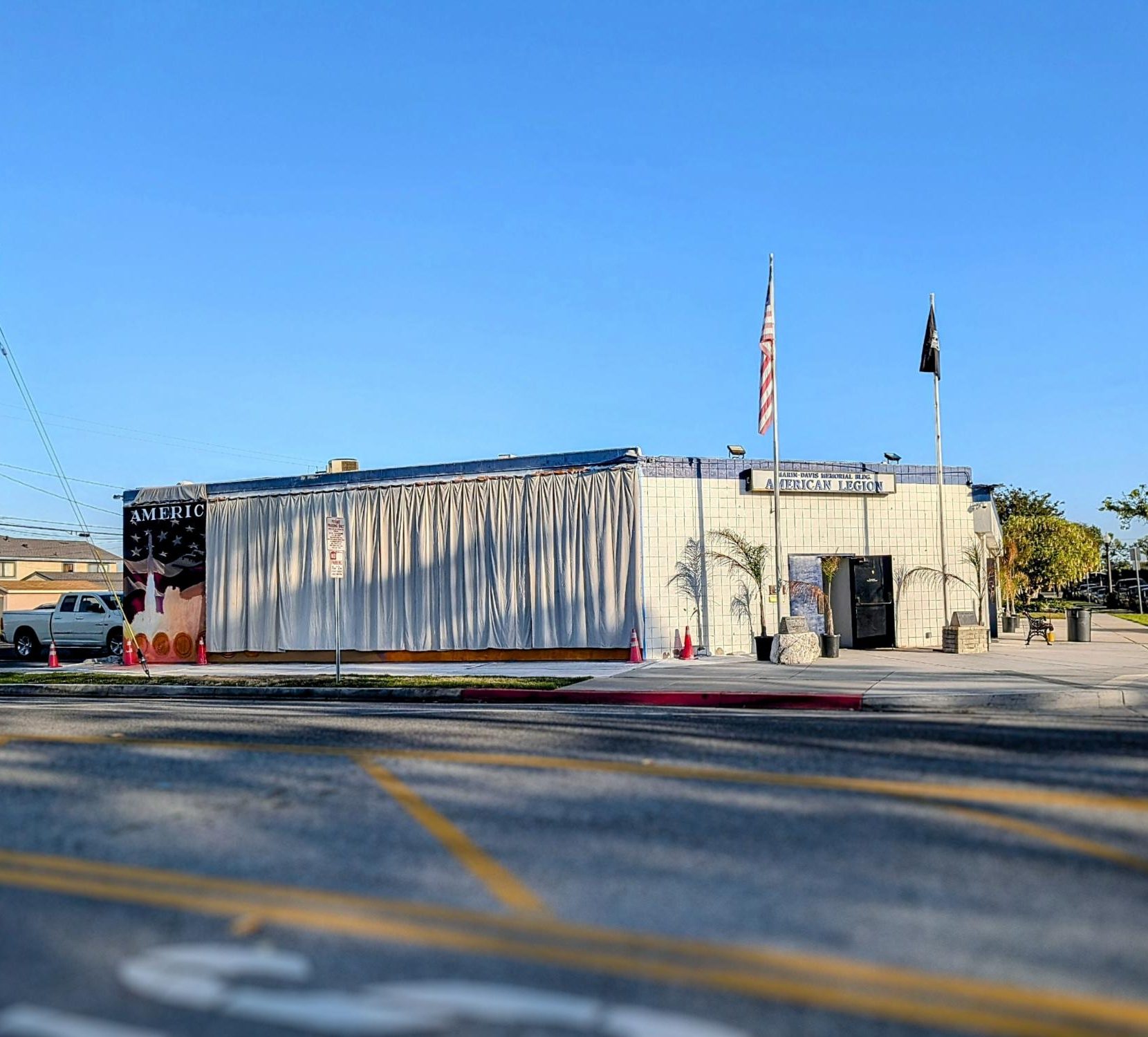 The American Legion Marin-Davis Post 716 building currently features a white curtain covering the in-progress mural, showing only a small portion of the grand art piece.