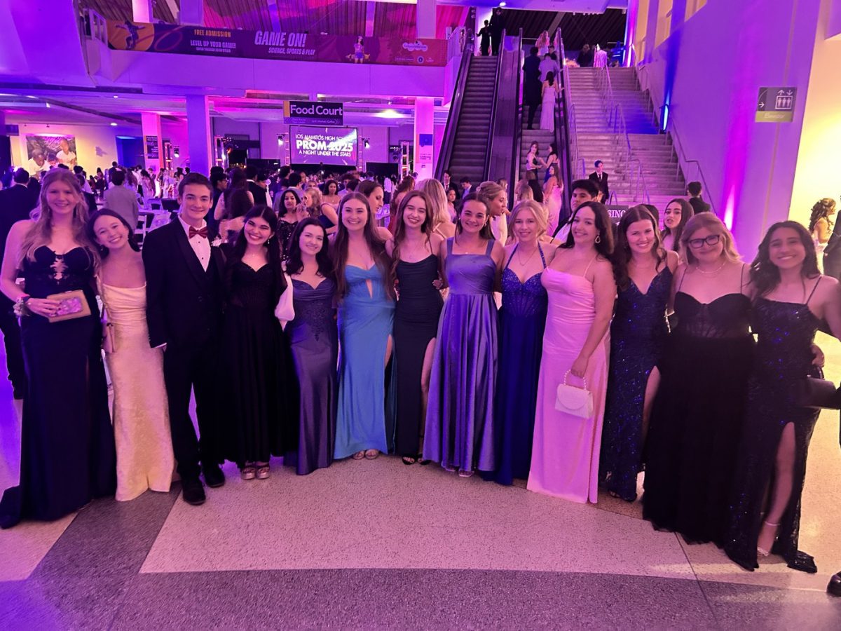 Prom attendees stand in the lobby of the Science Center, where the dance floor is in the center of the room and escalators lead to upper levels. (Photo courtesy of the LAHS weekly newsletter)