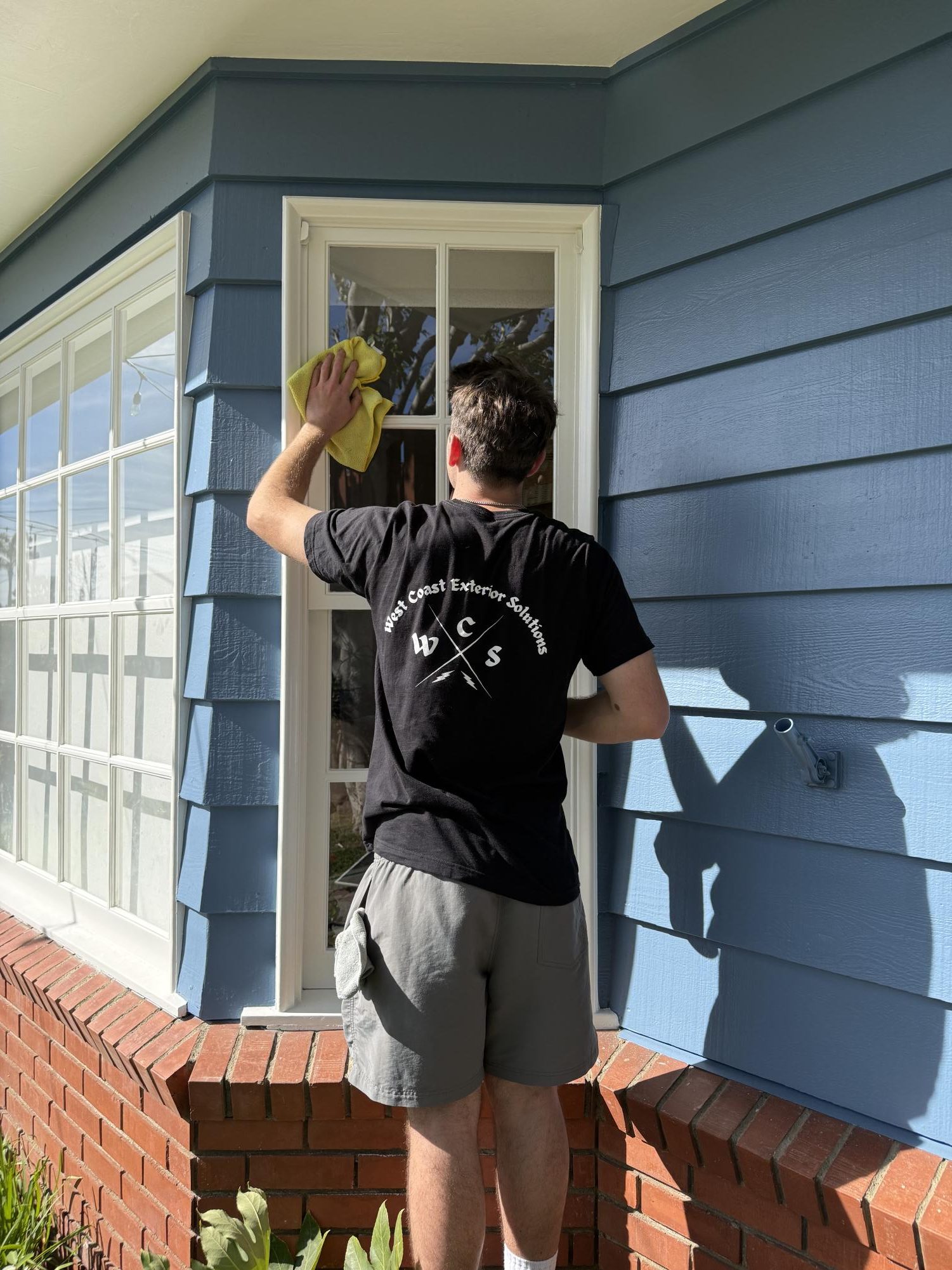Derek Baker, co-owner of West Coast Exterior Solutions, wiping down a window.