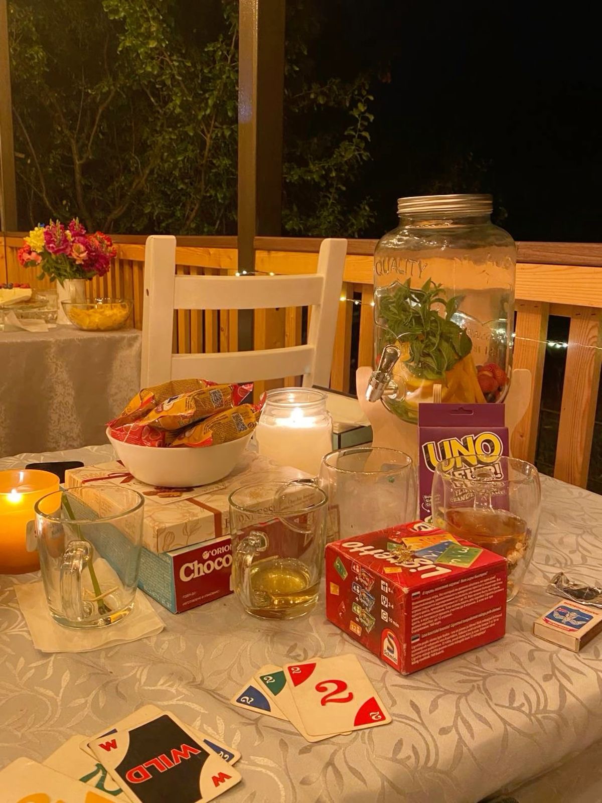 Stacks of card games on a table outside with candles. 